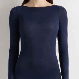 Marinblå långärmad topp från Intimissimi - Slimmad marinblå topp från Intimissimi med lång ärm och rundad halsringning. Tunn och mjuk känsla, perfekt att styla med jeans eller kjol. Materialet är merinoull som gör den extra skön och lätt. Enkel och stilren design utan detaljer. Har en liten defekt på ryggen, men de syns knappt!