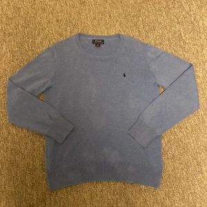 Blå stickad tröja från Polo Ralph Lauren - Snygg blå stickad tröja från Polo Ralph Lauren i storlek XL (barnstorlek) Passar Si vuxenstorlek. Tröjan har rund hals, långa ärmar och den klassiska broderade loggan på bröstet. Perfekt för dig som gillar stilrena och tidlösa plagg med en chill vibe.priset är inte skrivet i sten. Skriv vid minsta fundering.