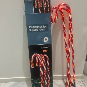 Polkagriskäpp 3-pack 70cm med belysning - Dekorativa polkagriskäppar för utomhusbruk, 3-pack, 70 cm höga med inbyggd belysning. Perfekt för juldekoration. Fungerar och lyser starkt, mindre smuts på markspett men i gott skick. Skapar en mysig stämning i trädgården eller vid entrén.