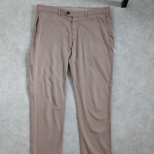 Canali, byxor, Chinos, beige, stl 52– FYND! - Säljer dessa tidlösa Canali Chinos i Cotton Twill-kvalitet. Ett perfekt basplagg som lyfter din vardagsstil eller fungerar utmärkt för en dressad look.  Midjemått ca 90cm, Innerbenslängd ca 79cm   Skick & Behov av Kärlek, 1.  Sömmen i grenen behöver fästas (enkel åtgärd). 2.  Det finns en mindre ljus fläck upptill på framsidan, men denna syns ej om du bär en tröja/skjorta över.  Perfekt för dig som vill ha ett par chinos från Canali till ett toppenpris och kan fästa sömmen själv! Nypris 3599 kr