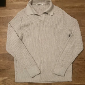 Beige stickad tröja med krage Reserved - Säljer en beige stickad tröja från Reserved i storlek M. Tröjan har ribbat mönster, klassisk krage och lång ärm. Perfekt för lager-på-lager och chill stil. Passar dig som gillar enkel men snygg design.