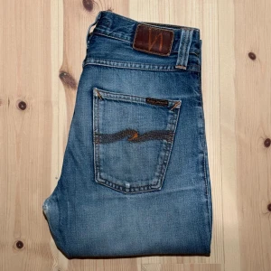 Nudie Jeans Steady Eddie - Tja! Säljer dessa riktigt snygga Steady Eddies i färgen whistle blue. Jeansen är i bra skick men har slitningar mellan benen och en slitning på låret. Enligt mig tycker jag att slitningen på låret ser snyggt ut och gör jeansen mer unika. Jeansen är i storleken W28/L34. Hör av dig vid funderingar!🙌