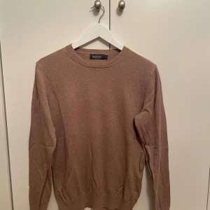 Beige tröja - En stilren beige tröja från Dressmann i mjuk Supima-bomull. Tröjan har rund halsringning, långa ärmar och ribbade muddar vid ärmslut. Storlek S