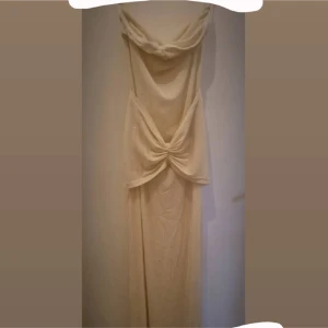 Champagnefärgad långklänning  - Supersnygg långklänning i champagnefärg med enkelt lite glittriga. Klänningen är axelbandslös, tunt transparent material men extra typ vid brösten och där nere som ni kan se på bilden. Den är S men passar M oxå. (om man har små bröst så är den nog enkel att åka mer om man inte använder dubbelhäftande hud-tejp under, bara så ni vet liksom)