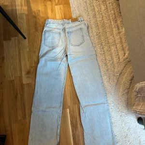 Ljusblå raka jeans - Säljer ett par ljusblå jeans med rak passform och fransad rå kant längst ner. Jeansen har klassiska fem fickor, knapp och dragkedja framtill samt slitna detaljer vid fickorna. Perfekt för dig som gillar en chill och avslappnad stil.