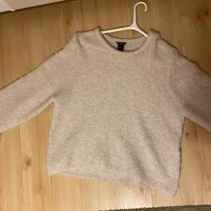Beige fluffig stickad tröja H&M - Supermjuk och fluffig beige stickad tröja från Lindex. Tröjan har en avslappnad passform, rund halsringning och långa ärmar. Materialet är mysigt och ger en cozy vibe.