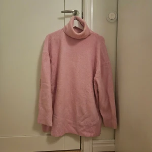 Rosa polotröja från Zara i storlek L - Mysig rosa polotröja i längre modell från Zara i storlek L. Tröjan har en hög, ribbad polokrage och är långärmad med avslappnad passform. Perfekt för kyliga dagar och enkel att styla med jeans eller kjol.Innehåller 6 % ull