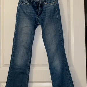 Blå bootcut jeans med klassisk tvätt - Snygga blå jeans med bootcut passform och klassisk tvätt. Jeansen har fem fickor, normal midja och subtila slitningar för en cool look. Perfekta för dig som gillar en avslappnad men ändå trendig stil.