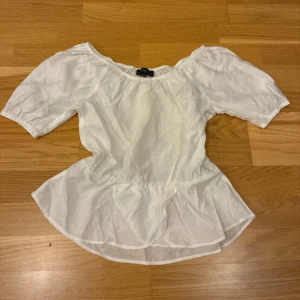 Vit blus från XO Friends - Säljer en söt vit blus från XO Friends i storlek 158/164 (men passar xs). Blusen har offshoulder-design med korta puffärmar och en volang nedtill som ger en feminin och trendig look. Perfekt för dig som gillar romantisk stil och vill ha något luftigt till sommaren.