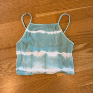 Turkos och vit ribbad linnetopp Zara - Säljer en fräsch turkos och vit ribbad linnetopp från Zara i storlek S. Toppen har smala axelband och ett coolt batikmönster. Materialet är mjukt och stretchigt, perfekt för varma dagar. Supersnygg att matcha med jeans eller shorts!