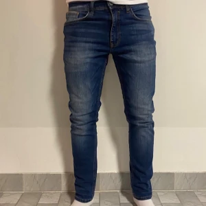 Blå slim jeans från Blend W29 L30 - Snygga blå jeans från Blend i modellen slim fit. Jeansen har klassisk femficksdesign, normal midja och lätt slitna detaljer framtill. Tillverkade i stretchigt denim för en bekväm passform. Perfekta för dig som gillar en smal siluett.