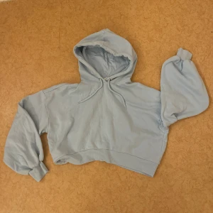 Ljusblå croppad hoodie - Superfin ljusblå hoodie från Monki med croppad passform och oversized ärmar. Endast använd 1-2 gånger. Hoodien har huva med snörning och breda muddar vid ärmslut och midja. Perfekt för en chill och avslappnad stil. ☺️🌹