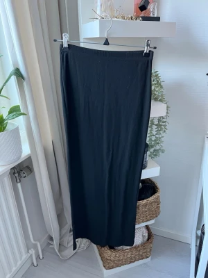 Svart ribbad långkjol - Säljer en svart ribbad långkjol med stretchig passform. Kjolen är enkel och stilren, perfekt till sneakers eller boots. Materialet är mjukt och följsamt, vilket gör den riktigt bekväm att bära. Från SHEIN 