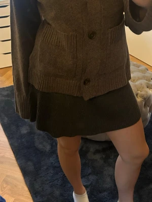 Mörkgrå stickad kjol från Zara - Supersnygg mörkgrå stickad kjol från Zara i kort modell. Kjolen har en ribbad struktur och sitter skönt i midjan. Perfekt att styla med en oversized tröja eller en tight topp för en chill look.