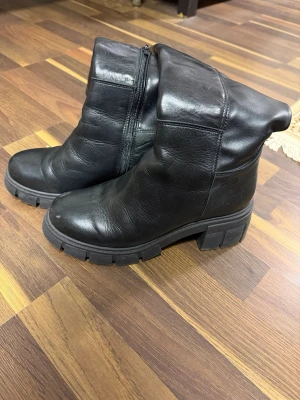 Svarta chunky läderstövlar Dasia - Säljer ett par svarta höga stövlar i skinn med chunky sula och dragkedja på sidan. Använda endast två gånger och Inköpta för 1900. Stövlarna har en rund tå och grov yttersula som ger en cool look. Perfekta till höst- och vinteroutfits för dig som gillar en edgy stil.