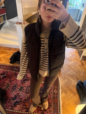 Svart dunväst från Zara - Säljer en svart dunväst från Zara i storlek 152. Västen har hög krage och quiltad design, perfekt att slänga över en stickad tröja för en chill look. Enkel att matcha och riktigt skön att bära under höst. Den är storlek 152 men skulle säga att den är stor i storleken.