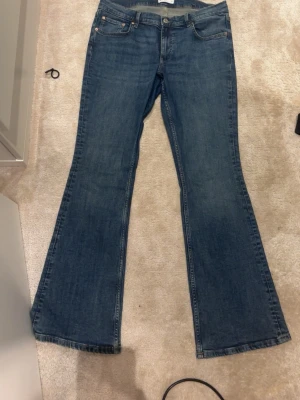 perfekt jeans ginatricot ,bootcut, storlek 44 - Säljer ett par klassiska blå jeans från gina med bootcut passform. Jeansen har fem fickor, snygga kopparfärgade nitar och en läderpatch bak i midjan.  knappast använda.