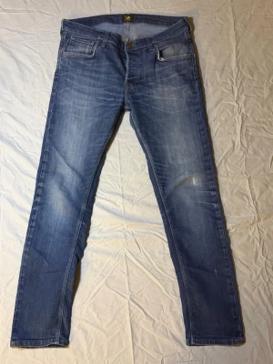 Lee Jeans Mörkblå – W34 L32 – Bra skick – Sjukt snygga - Säljer ett par Lee jeans i mörkblå färg, storlek W34 L32, i bra skick. Klassisk färg och tvätt som funkar till allt – enkla att styla både casual och mer uppklätt.  Snygg passform och bekväm känsla. Ett stabilt par jeans för vardagsbruk.  • Märke: Lee • Färg: Mörkblå • Storlek: W34 L32 • Skick: Bra skick • 100 % original  Snabb leverans. Säker betalning via plattformen.  Lee 2