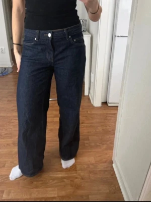 Low wide petite mörkblå jeans gina tricot - Säljer ett par mörkblå jeans från gina tricot modellen low wide petite storlek 36. Modellen är wide med raka, breda ben och klassisk femficksdesign. Jeansen har normal passform och är tillverkade i jeansmaterial med knapp och dragkedja framtill. 