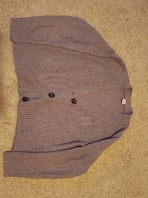 Ljuslila kofta från Lindex - Mysig ljuslila kofta från Lindex med ribbad struktur och stora knappar framtill i storlek 146/152. Koftan har lång ärm och en klassisk v-ringad design. Pris kan diskuteras vid snabba köp😍