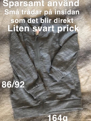 Grå zip-hoodie i ull - Mysig grå hoodie med dragkedja framtill och långa ärmar. Tröjan har en enkel design utan tryck, ribbade muddar och är tillverkad i ett ull. Perfekt för lager-på-lager under kyliga dagar.🌸 Sparsamt använd. Små trådar på insidan som det blir direkt på dessa (ej hål). Liten svart prick på armen som jag såg nu vid granskning. 86/92