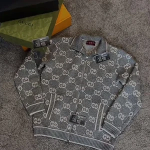 Gucci cardigan zip up hoodie - Säljer en grå stickad kofta från Gucci med vit GG-logga över hela tröjan. Koftan har dragkedja framtill, ribbad krage och muddar samt två fickor med vita detaljer. Perfekt för dig som gillar lyxiga märken och snygg design. Helt ny oanvänd prislapp finns pris kan diskuteras skriv vid frågor