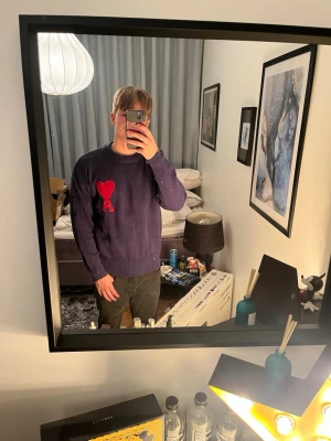 Mörkblå stickad tröja från Ami Paris - Säljer en mörkblå stickad tröja från Ami Paris med röd hjärt- och A-detalj på bröstet. Tröjan har rund halsringning, ribbade muddar och är långärmad. Perfekt för dig som vill ha en stilren men ändå unik look.