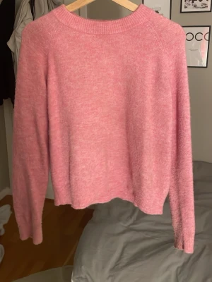 Rosa stickad tröja  - Mysig rosa stickad tröja med rund hals och långa ärmar. Tröjan har ribbade muddar vid hals, ärmslut och nederkant. 