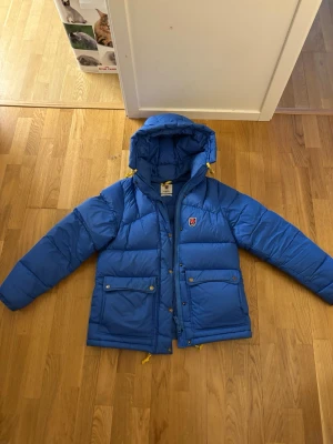 Ljusblå dunjacka från Fjällräven - Ljusblå dunjacka i storlek M från Fjällräven BYTES mot en mörkblå eller svart, i storlek S eller M. Kan även tänka mig sälja den för 5500.