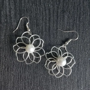 Silvriga handgjorda örhängen med pärldetalj - Egentillverkade örhängen i form av blommor gjord med silverfärfade metalltrådar och en vit pärla i mitten. Perfekta för dig som vill ha något annorlunda och stilrent som sticker ut. Blomman är ca 3cm stor