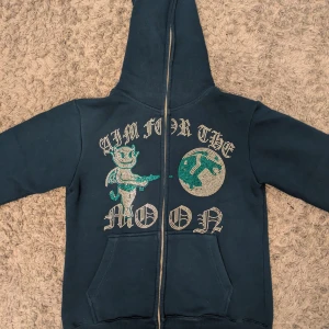 Mörkblå hoodie Aim For The Moon - Säljer en mörkblå hoodie från Aim For The Moon i storlek M. Tröjan har huva, dragkedja och känguruficka. 