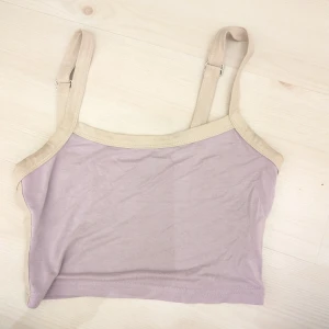 Ljuslila croppad linne från SHEIN - Säljer en ljuslila croppad linne från SHEIN med beige kantband och justerbara axelband. Materialet är mjukt och stretchigt. Passar även XS