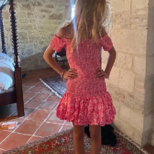 Rosa offshoulder kortklänning - Superfin rosa kortklänning med offshoulder och volang nedtill. Klänningen har ett blommigt mönster och är perfekt för sommarens alla tillfällen. Sval och skön passform med elastisk överdel och korta ärmar.