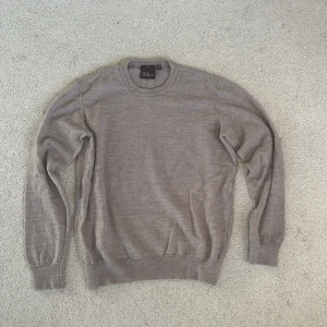 Grå ulltröja från Oscar Jacobson - Säljer en stilren grå tröja från Oscar Jacobson i mjuk ull. Klassisk rund halsringning och ribbade muddar vid ärmslut och nederkant. Perfekt för lager-på-lager och passar till allt. Enkel och tidlös design som funkar året om. Har råkat krympt den i tvätten så skulle säga att det snarare är en XS än en S.
