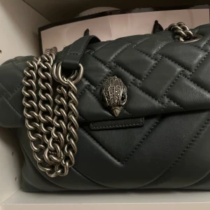 Mörkgrön Kurt Geiger Väska - Säljer min så fina Kurt Geiger väska, då den tyvvär inte kommer till användning längre. Väskan är i den större modellen och i mycket bra skick förutom några små repor. Pris kan diskuteras och jag skulle även kunna tänka mig att byta mot någonting i samma prisklass!!❤️