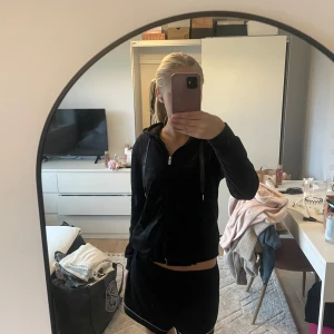 Svart hoodie från Gina Tricot - Svart hoodie från Gina Tricot med dragkedja framtill och snörning i huvan. Mjuk och skön, perfekt för chill dagar. Långärmad modell med normal passform och fickor på sidorna. Klassisk look som funkar året runt.