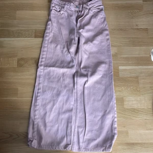 Ljuslila wide jeans i bomull, stl 25 - Säljer ett par ljuslila jeans med wide fit och hög midja. Byxorna är tillverkade i 100% bomull och har klassisk femficksdesign. Perfekta för dig som gillar en avslappnad och trendig look.