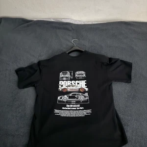 Porsche tshirt - Tja! Säljer min helt nya Porsche tshirt då den inte kommer till någon användning. T-shirten har en logga på baksidan men är helt svart på framsidan. Tröjan är aldrig använd utomhus utan bara testats vilket gör att den är helt ny. Fråga gärna!