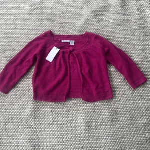  Söt Mörkrosa kofta/bolero från Matin Blanc - Supersöt mörkrosa kofta från Matin Blanc med trekvartsärmad och knytband framtill. Koftan är stickad i mjukt material och har fina virkade detaljer vid halsringning och nederkant. Perfekt för lager-på-lager och snygg till både jeans och klänning. Supersöt❤️