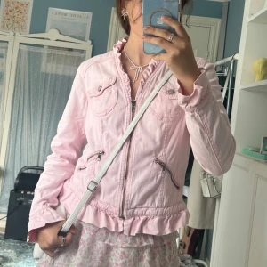 Ljusrosa jacka med volang från KappAhl - Supersöt ljusrosa jacka från KappAhl med volangdetaljer vid krage, ärmslut och nederkant. Den är i storlek 40, men skulle säga att den sitter som en 38a!💕💕Den är köpt second hand, men har tyvärr inte använts av mig.🩷 Skriv vid fler frågor!💐🌷
