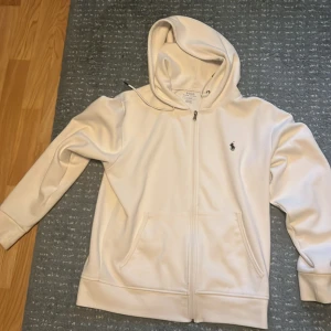 Vit hoodie från Polo Ralph Lauren - Snygg vit hoodie från Polo Ralph Lauren ganska fin skick har inga märken eller nåt är bara lite förliten för mig. Men kan sälja den för lite mindre