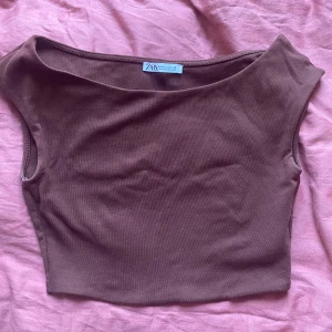 Brun croppad topp från Zara - Säljer en brun croppad topp från Zara i storlek M. Använt endast 2 gånger då jag inte tar på mig crop tops. Toppen är ärmlös med breda axelband och har en enkel, stilren design. Materialet är mjukt och stretchigt, perfekt för en avslappnad look och basic look. 