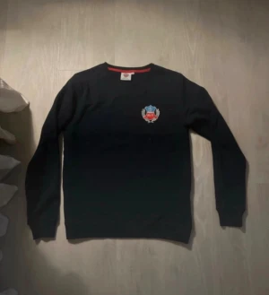 Marinblå  Helsingborgs IF tröja XS - Marinblå långärmad tröja från Helsingborgs IF med klubbens emblem broderat på bröstet. Rund hals med röd insida som ger en snygg kontrast. Perfekt för dig som vill visa ditt stöd för laget och gillar enkel, sportig stil.