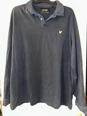 Mörkblå långärmad tröja Lyle & Scott strl: XXL - Mörkblå långärmad skjorta från Lyle & Scott i storlek XXL. Skjortan har klassisk krage, knappar framtill och på ärmsluten samt den ikoniska gula fågeln broderad på bröstet. Tillverkad i mjuk bomull som är skön mot huden. Ev tvättpåvärkan förekommer.