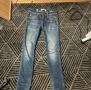 Replay blå skinny jeans - Snygga blå jeans från Replay med skinny fit och klassisk femficksdesign. Jeansen har slitningar och ljusare partier framtill för en cool, använd look. Perfekta för dig som gillar en smal siluett och vill ha ett par jeans som sticker ut. Jeansen har fler slitningar nu än vad det är på bilden, kan skicka via dm!