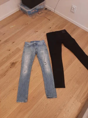Replay och dondup ljusa och svarta skinny jeans - Två par jeans från Replay och dondup, ett par ljusblå med slitningar och ett par helsvarta. Båda har skinny passform och klassiska femficksdetaljer. De ljusblå har slitna detaljer framtill och logga på bakfickan, medan de svarta är stilrena och enfärgade. Riktigt bra pris för båda 899kr skynda att fynda! Dondup jeansen 30w 32L replay 30w 32L