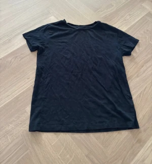 Svart t-shirt från 157 i bomull - En basic svart t-shirt från 157 i 100% ekologisk bomull. Klassisk rund halsringning och korta ärmar. Perfekt till jeans eller shorts för en enkel och clean look.