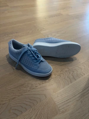 Ljusblå sneakers från Clou Comfort - Snygga ljusblå sneakers från Clou Comfort i storlek 39. Använt en gång!! Skorna har stickade detaljer på sidorna, snörning framtill och en vit platt sula. Perfekta för dig som gillar en sportig och fräsch look med en twist av stickad känsla.