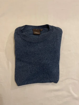 Blå rundhalsad tröja Oscar Jacobson - Snygg blå rundhalsad tröja från Oscar Jacobson i storlek S. Tillverkad i Italien med mjukt och skönt material som känns lyxigt. Tröjan har lång ärm och klassisk passform, perfekt för dig som gillar stilrena och enkla plagg.