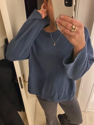 Blå stickad tröja från 157, storlek M - Mysig blå stickad tröja från 157 i storlek M. Tröjan har en rund halsringning, långärmade och loose passform. Materialet är mjukt och har en lite fluffig struktur som gör den extra skön att bära. Perfekt för kyliga dagar och enkel att matcha med jeans eller mjukisbyxor.